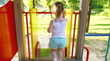 mother and baby play on the playground. little kid laughs and enjoys the playground in the park. child plays with mom on the street.