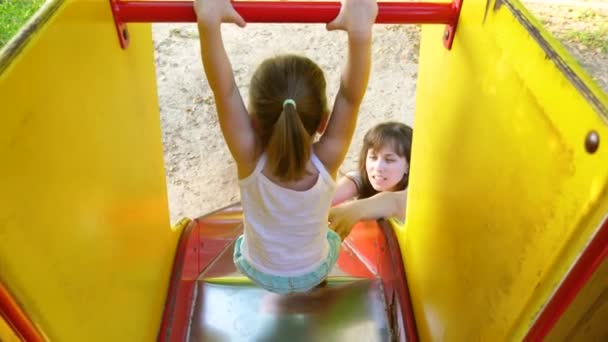 Little kid laughs and enjoys the playground in the park. child plays with mom on the street. mother and baby play on the playground. Slow motion — 비디오