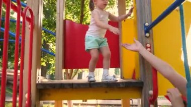 Mutlu çocukluk ve aile kavramı. Küçük çocuk gülüyor ve parktaki oyun alanının tadını çıkarıyor. Çocuk, annesiyle sokakta oynuyor. Anne ve bebek parkta oynuyorlar. Mutlu çocukluk kavramı.