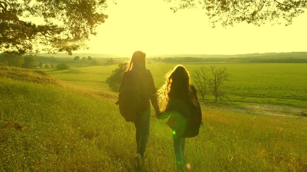 Lavoro di squadra tra ragazze escursioniste. ragazze viaggiatore libero alzano le mani, celebrando la vittoria e godendo il paesaggio, al sole. donne felici in vacanza viaggiano attraverso i boschi con lo zaino, alzano le mani . — Foto Stock