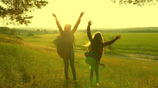 Ведучі дівчата працюють в команді. безкоштовні мандрівники піднімають руки, святкуючи перемогу і насолоджуючись пейзажами, на сонці. щасливі жінки у відпустці подорожують лісом з рюкзаком, піднімають руки вгору . — стокове фото
