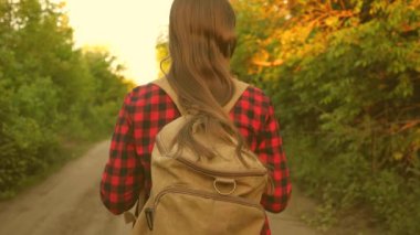 Özgür kız bir sırt çantasıyla ormanda yürüyor. Yürüyüşçü kadın ormanda yürüyor. Yaz parkındaki mutlu yürüyüşçü kız. Genç kız tatilde maceralar yaşıyor. yakın plan.