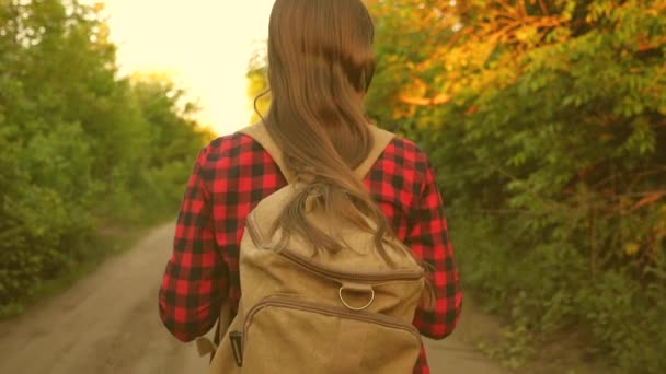 Volný dívka cestovatel se prochází lesem s batohem. Turistka chodí po lese. šťastná turistka v letním parku. teenager dívka dobrodružství na dovolené. close-up. — Stock video