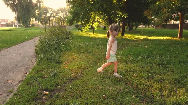 Barnet leker i parken på våren. Sakta i backarna. Grabben leker på gräsmattan på sommaren. Glada barn springer på en äng på sommaren på ett grönt gräs. Glada lilla flicka springer över fältet. begreppet lycka. — Stockfoto
