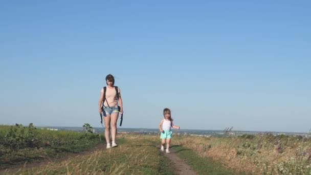 子供のいる旅行者の母親は、道路を歩く。母と娘は町を出る。楽しい子が道を走ってる。幸せな子供時代と家族の概念. — ストック動画