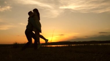 Seksi çift gün batımında kumsalda kolayca dans eder. Deniz kenarında parti var. Aşıkların ışık dansı harika bir akşamda. Mutlu erkek ve kadınların takım çalışması..