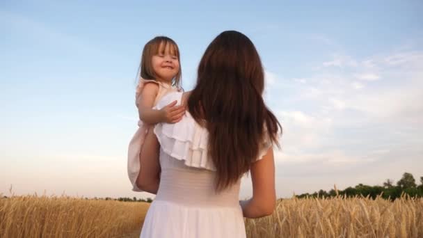 Mama i mała córka grają na polu dojrzałej pszenicy w słońcu. matka idzie z dzieckiem w polu z pszenicą. szczęśliwych podróży rodzinnych. dziecko w ramionach Mama. Szczęśliwa rodzina koncepcja. — Wideo stockowe