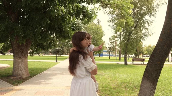 Bela mãe carrega uma pequena filha no parque ao ar livre. Bela mãe e seu bebê estão brincando no parque. bebê e abraços mãe feliz. Feliz Dia das Mães Alegria. Mãe e bebé. 4K — Fotografia de Stock