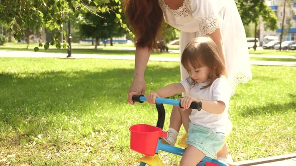 Kind lernt Fahrradfahren. Konzept einer glücklichen Familie und Kindheit. Eltern und kleine Tochter spazieren im Park. Glückliche Mutter bringt ihrer kleinen Tochter das Fahrradfahren bei. Mutter spielt mit Kind im Freien. — Stockfoto