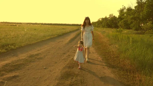 母亲和婴儿在公园休息.幸福童年的概念。小女儿和妈妈走在穿过田野的路上。孩子们在玩逃避妈妈的游戏。有孩子的幸福家庭在农村散步. — 图库照片