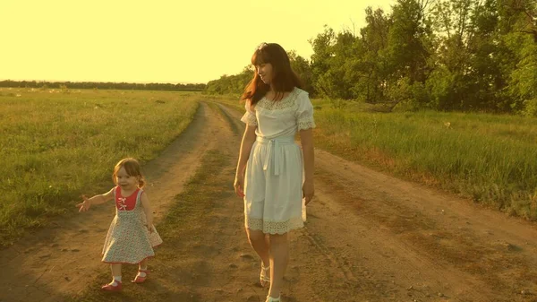 Mor och barn vilar i parken. begreppet lycklig barndom. Lilla dottern och mamma går längs vägen förbi åkern. Barnet leker rymma från mamma. lycklig familj med ett barn promenader på landsbygden. — Stockfoto