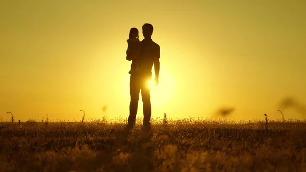 Щасливий тато з маленькою дочкою на руках на заході сонця. батько і дитина гуляють в парку. щаслива сім'я з малюком гуляє в полі на заході сонця. концепція щасливої сім'ї та дитинства . — стокове фото