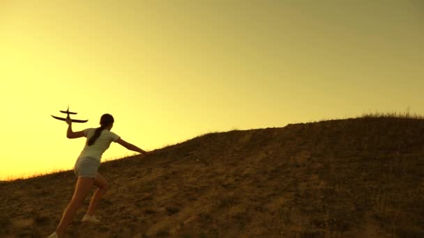 Silhouette of children playing on plane. Children run up mountain with an airplane in hand at sunset. Dreams of flying. Happy childhood concept. girls play with a toy plane at sunset. — ストック動画