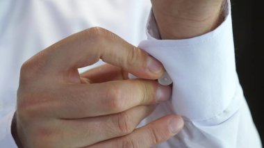 young businessman going to a business meeting. Mens hands fasten a button on the sleeve of a white shirt. a man puts on clothes in the morning to work. office worker. Man dressing close-up.