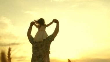 Çocuk ve baba olgunlaşan buğday tarlasında oynuyorlar. Küçük kız babasının omuzlarında. Bebek ve babası sahada seyahat ediyor. Çocuk ve ebeveyn doğada oynuyorlar. Mutlu aile ve çocukluk kavramı