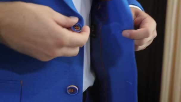 O homem na moda fixa botões em uma jaqueta azul. close-up. O homem elegante em um terno fixa botões em uma jaqueta, prepara-se para a saída. empresário se vestir para o trabalho . — Vídeo de Stock
