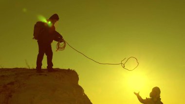 Dağcılar bir iple dağa tırmanırlar. Kız gezgin kendini kaybediyor ve uçurumdan düşüyor. Turistlerin takım çalışması. Gün batımında dağlarda dolaşmak. İş adamları birbirlerini sigortalarlar. Zor durumlarda yardım.