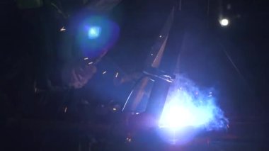 Metal işleme tesisinde endüstriyel üretim yapan metal yapıları kaynak yapmak için modern kaynak makinesi kullanan koruyucu bir maske takan endüstriyel işçiler. Parlak ışık ve kaynaktan kıvılcımlar.