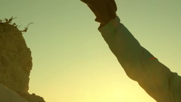 Gli scalatori viaggiatori scalano la montagna aiutandosi a vicenda. Donna libera, viaggiatore scalare la montagna tenendosi per mano. lavoro in team di turisti. gita in montagna al tramonto. Gli uomini d'affari si assicurano a vicenda. primo piano — Video Stock