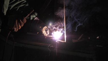 Parlak ışık ve kaynaktan çıkan kıvılcımlar. Metal işleme tesisinde endüstriyel üretim yapan metal yapıları kaynak yapmak için modern kaynak makinesi kullanan koruyucu bir maske takan endüstriyel işçiler..