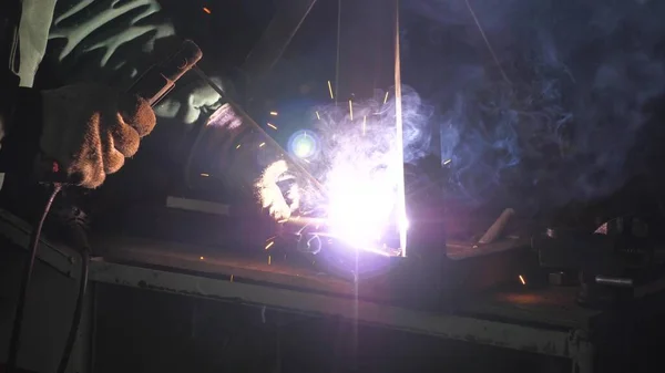 Parlak ışık ve kaynaktan çıkan kıvılcımlar. Metal işleme tesisinde endüstriyel üretim yapan metal yapıları kaynak yapmak için modern kaynak makinesi kullanan koruyucu bir maske takan endüstriyel işçiler.. — Stok fotoğraf