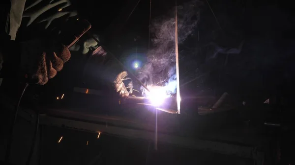 Parlak ışık ve kaynaktan çıkan kıvılcımlar. Metal işleme tesisinde endüstriyel üretim yapan metal yapıları kaynak yapmak için modern kaynak makinesi kullanan koruyucu bir maske takan endüstriyel işçiler.. — Stok fotoğraf