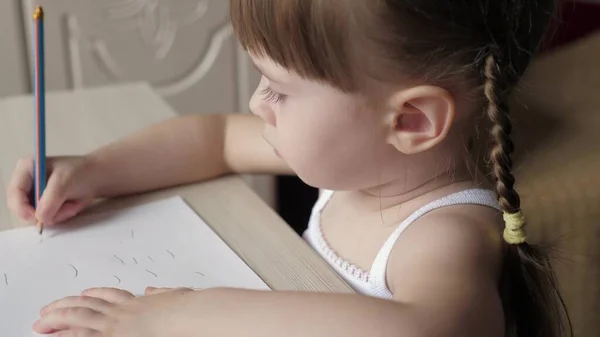 Concepto de desarrollo infantil. niño dibuja en una hoja de papel blanco. Lindos lápices de colores de niña artista en una habitación en una mesa. niño preescolar inteligente enfocado disfrutando del arte creativo hobby en la actividad en el hogar . — Foto de Stock