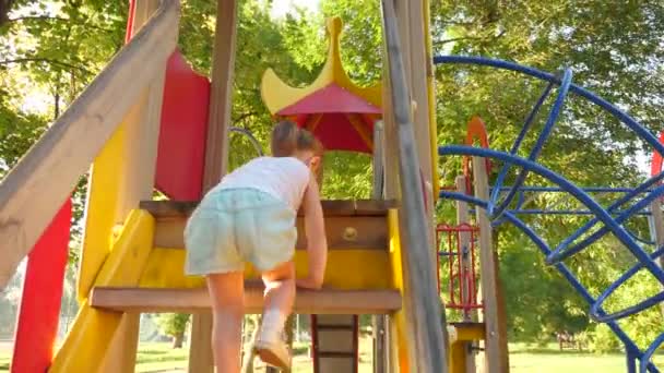 Concepto de infancia feliz. niño sube las escaleras hasta el tobogán de niños. madre y bebé juegan en el patio de recreo. feliz infancia y concepto familiar. niño se ríe y disfruta de parque infantil en el parque — Vídeo de stock