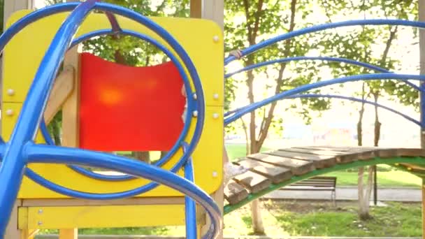 Niño feliz corre en el patio de recreo al sol. feliz infancia y concepto familiar. niño se ríe y disfruta del parque infantil en el parque. madre y el bebé juegan en el patio de recreo. concepto de una infancia feliz . — Vídeo de stock