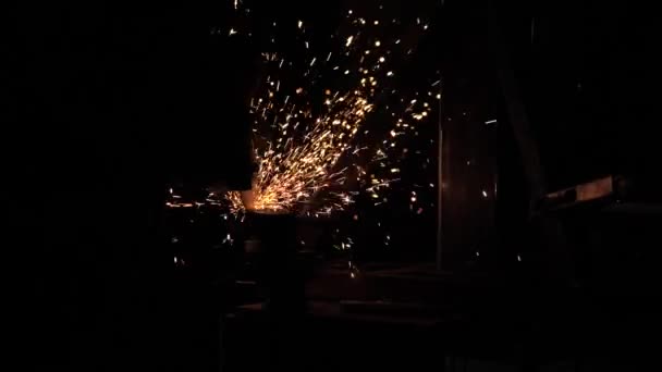 En arbetare på en fabrik bearbetar metallgnistor flyga. Cirkulär såg skär metall i en verkstad. Man jobbar på erövraren. metallbearbetning i en fabrik. Långsamma rörelser — Stockvideo