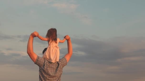 Child and parent play in nature. little happy daughter on fathers shoulders in the field against blue sky. baby boy and dad travel on a wheat field. happy family and childhood concept. Slow motion — Stock Video