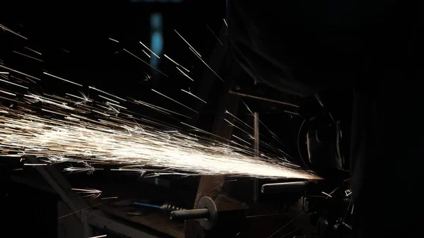 Un ouvrier d'une usine traite du métal, des étincelles volent. Gros plan. Scie circulaire coupe le métal dans un atelier. L'homme travaille sur le conquérant. métallurgie dans une usine . — Photo
