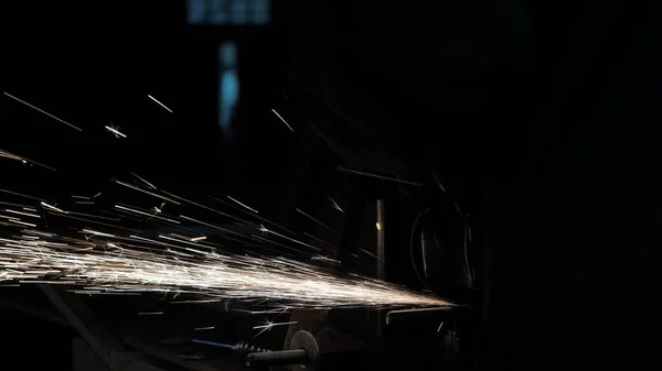 Un trabajador en una fábrica procesa metal, chispas vuelan. Primer plano. La sierra circular corta metal en un taller. El hombre trabaja en el conquistador. metalurgia en una fábrica . — Foto de Stock