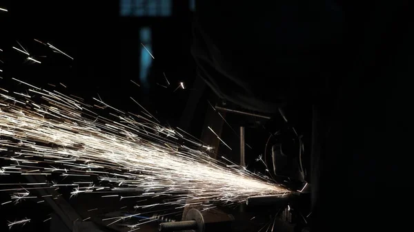 Un ouvrier d'une usine traite du métal, des étincelles volent. Gros plan. Scie circulaire coupe le métal dans un atelier. L'homme travaille sur le conquérant. métallurgie dans une usine . — Photo