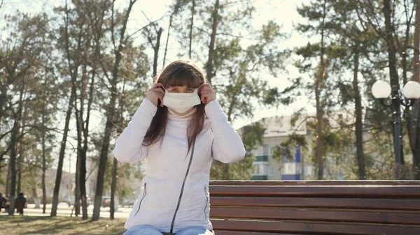 一个戴着防护面具的小女孩在街上。大流行的大肠癌。坐在长椅上的公园里的女游客戴着防毒面具。概念、健康和安全、 N1H1高头牛、病毒保护. — 图库照片
