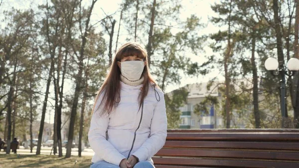 거리에서 보호용 마스크를 쓴 어린 소녀. 대유행 코로나 바이러스. 공원에서 벤치에 앉아 있는 여성 이 바이러스로부터 보호 마스크를 쓰고 있다. 컨셉트 건강 과 안전 , n1h1 코로나 바이러스, 바이러스 보호. — 스톡 사진