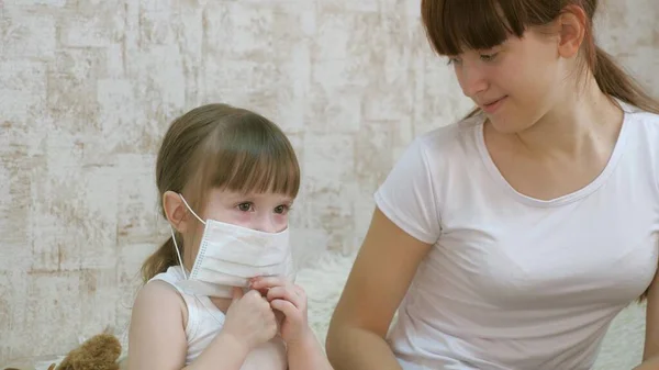Egy kislány karantén, orvosi maszkot tett egy játékmacira. a karonovírus és az influenza elleni védelem. A baba a kórházban játszik. gyerek játék orvos, nővér, állatorvos, kezelésére beteg. — Stock Fotó