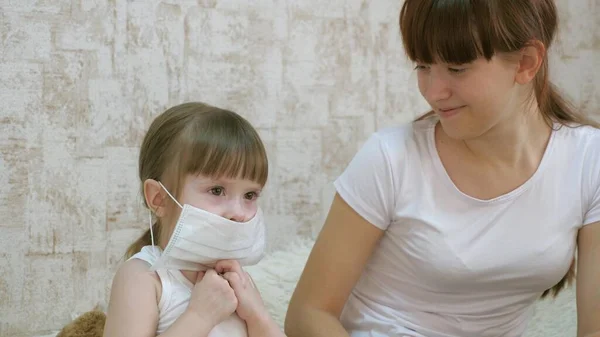 Egy kislány karantén, orvosi maszkot tett egy játékmacira. a karonovírus és az influenza elleni védelem. A baba a kórházban játszik. gyerek játék orvos, nővér, állatorvos, kezelésére beteg. — Stock Fotó