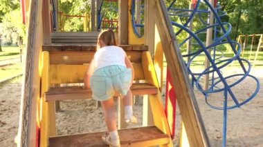 Mutlu çocukluk kavramı. Çocuk merdivenlerden çıkıp çocuklar kayıyor. Anne ve bebek oyun bahçesinde oynuyorlar. Mutlu çocukluk ve aile kavramı. Küçük çocuk gülüyor ve parkta oyun oynamaktan hoşlanıyor.