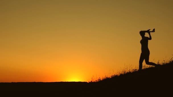 Kinder laufen mit dem Flugzeug in der Hand vor der Sonne vom Berg. Träume vom Fliegen. Glückliche Kindheit. Mädchen spielen bei Sonnenuntergang mit einem Spielzeugflugzeug. Silhouette von Kindern, die im Flugzeug spielen — Stockvideo