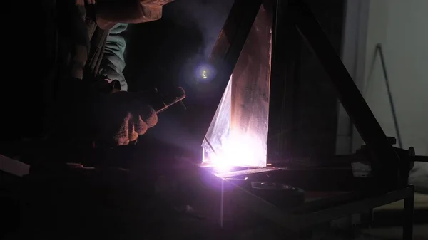 Lumière vive et étincelles de soudage. Travailleur industriel dans un masque de protection utilisant une machine de soudage moderne pour le soudage des structures métalliques dans la production industrielle dans une usine de traitement des métaux . — Photo