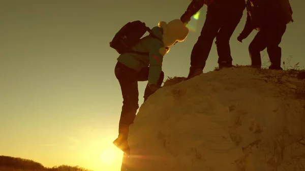 Equipo de escaladores sube una montaña que sostiene una mano de ayuda a los demás. Mujer viajera libre escalar la montaña. Trabajo en equipo de turistas. Viaje y aventura en las montañas al atardecer . —  Fotos de Stock