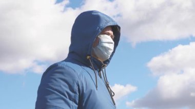Salgın Koronavirüs. Sokakta maskeli ve kapüşonlu yaşlı bir kadın. Kadın koruyucu maske takıyor. Sağlık konsepti. Koronavirüs N1H1 karantinası, virüs koruması. tehlikeli enfeksiyon