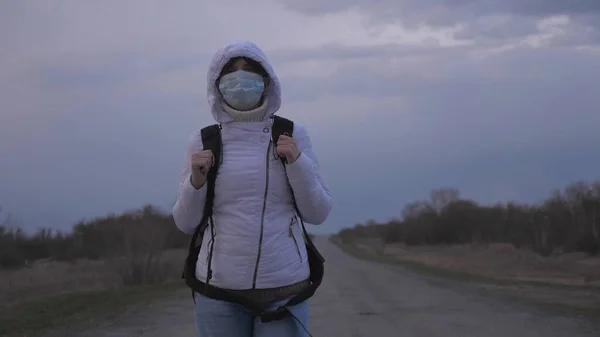 Бесплатная девушка путешественница с рюкзаком в защитной медицинской маске и капюшоном выходит из города по дороге. Защита от вирусов и бактерий. концепция безопасности и здоровья, коронавирус N1H1, вирус — стоковое фото