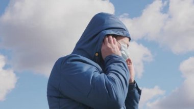 Enfeksiyon tehlikesi. Sokaktaki adam koruyucu bir maske ve başlık takıyor. Pandemik koronavirüs. Adam koruyucu maske takıyor. Sağlık konsepti. Koronavirüs N1H1 karantinası, virüs koruması.