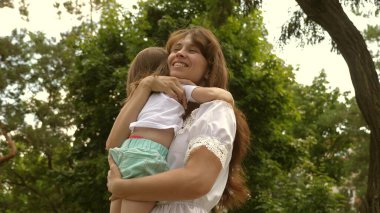 Annem mutlu bir çocuğu kucaklıyor. Güzel anne ve bebeği parkta oynuyorlar. Anneler Günün kutlu olsun. Anne ve bebek 4K. Mutlu çocukluk kavramı. Mutlu anne parkta küçük kızına sarılıyor..