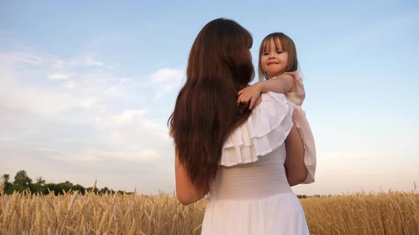 Šťastná rodina cestuje. dítě v náručí mámy. šťastný rodinný koncept. Máma a dcerka si hrají na poli zralý pšenice na slunci. matka chodí s dítětem na poli s pšenicí. — Stock fotografie