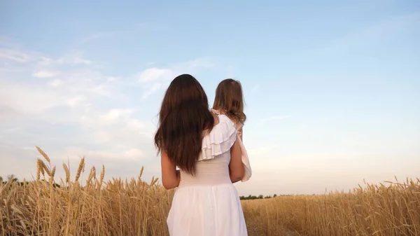 Famille heureuse voyage. bébé dans les bras de maman. concept de famille heureuse. Maman et petite fille jouent sur un champ de blé mûr au soleil. mère marche avec un enfant dans un champ de blé . — Photo
