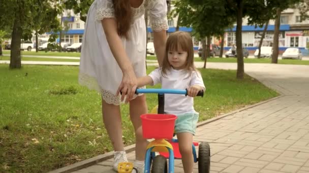 Ebeveynler ve küçük kızları parkta yürürler. Mutlu anne küçük kızına bisiklet sürmeyi öğretiyor. Anne bebeğiyle dışarıda oynuyor. Mutlu aile ve çocukluk kavramı. Çocuk bisiklet sürmeyi öğreniyor.. — Stok video