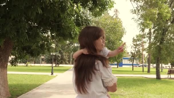 Bella madre porta una bambina nel parco all'aria aperta. Bella madre e il suo bambino stanno giocando nel parco. bambino e abbraccia la madre felice. Buona festa della mamma. Mamma e bambino. 4K — Video Stock